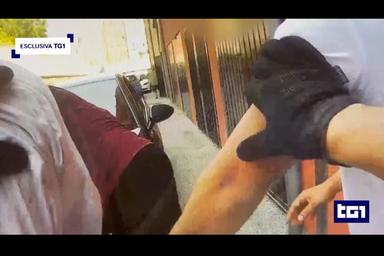 Scena di strada con intervento di agente di polizia durante operazione, corpo-cam in primo piano, immagine di approfondimento