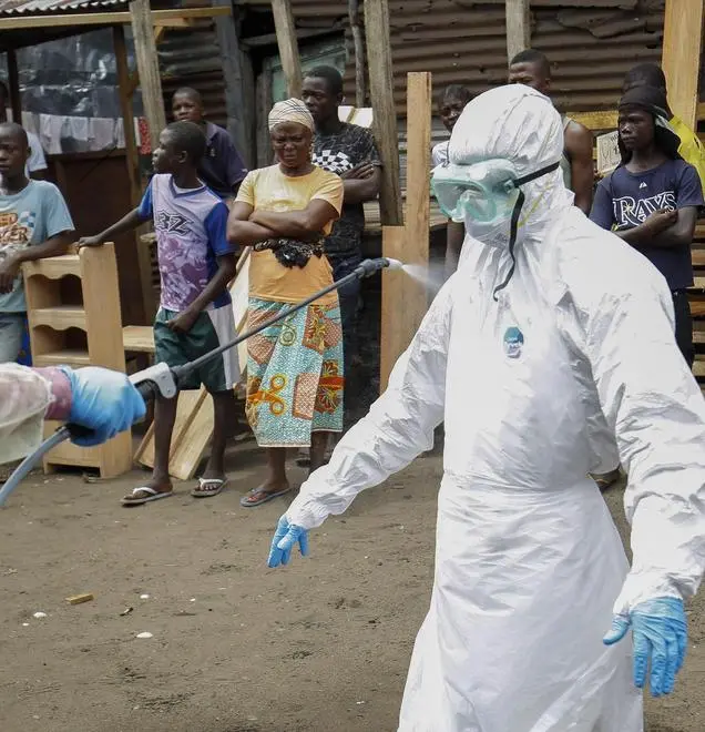 epaselect epa04446714 A Liberian health worker from a Red Cross burial team is disinfected during collection of bodies of Ebola victims in the Point Four community on the outskirts of Monrovia, Liberia, 14 October 2014. Latest statistics from the United Nations World Health Organization (WHO) place the death toll from the Ebola virus outbreak at 4,447 with most of those fatalities in West Africa. EPA/AHMED JALLANZO