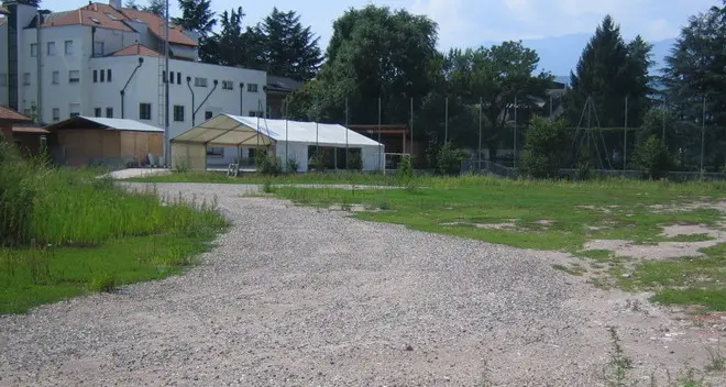 Sul campo da calcio un grande parco, case e un parcheggio