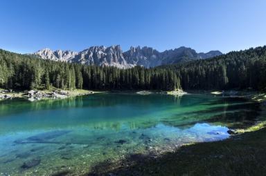 Uomo a difesa di un lago alpino tra le Dolomiti con montagne sullo sfondo, immagine di approfondimento