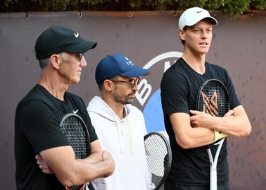 Allenatore durante una conversazione su un campo da tennis, con focus sulla gestione emotiva di un campione, immagine di approfondimento