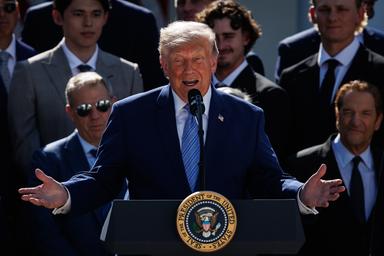 Donald Trump al podio, sfondo Casa Bianca, gesto minaccioso delle mani mentre parla, immagine di approfondimento