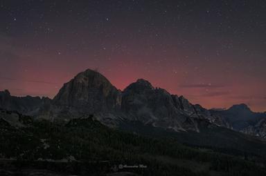 Un'aurora boreale colora di rosso il cielo delle Dolomiti